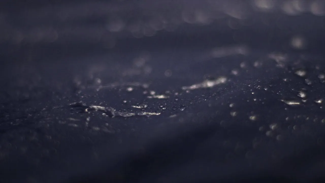 Water standing in beads on dark technical cloth, close enough to count them
